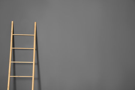 Modern wooden ladder on gray background. Space for textの写真素材