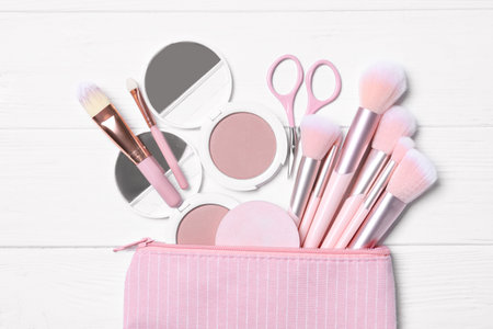 Cosmetic bag with makeup products and beauty accessories on white wooden backgroundの写真素材