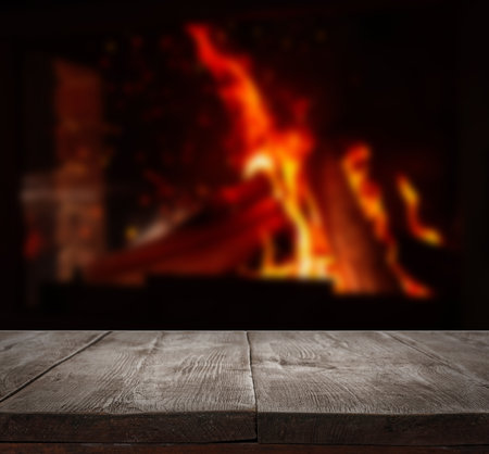 Rustic table and fireplace with burning wood indoorsの写真素材