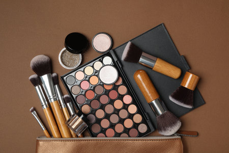 Cosmetic bag with makeup products and beauty accessories on brown background, flat layの写真素材