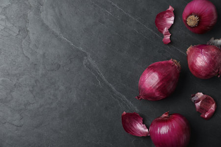 Ripe red onion bulbs on black table, flat lay. Space for textの写真素材
