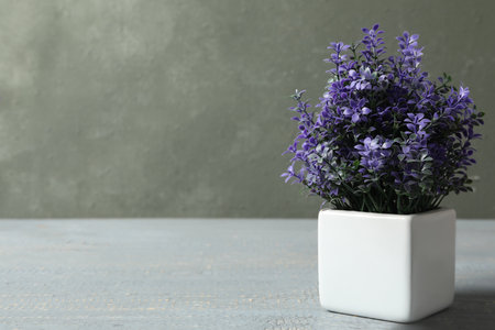 Artificial plant in white flower pot on grey wooden table. Space for textの写真素材