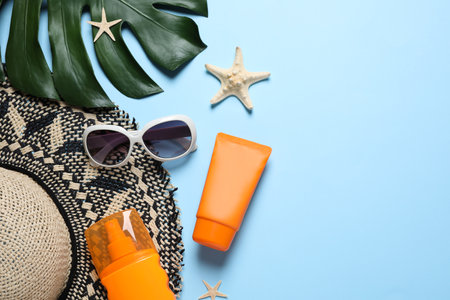 Flat lay composition with sun protection products and beach accessories on light blue background. Space for textの写真素材