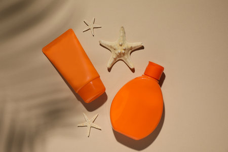 Sun protection products and starfishes on beige background, flat lay