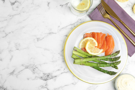 Tasty asparagus with salmon and lemon on white marble table, flat lay. Space for textの写真素材