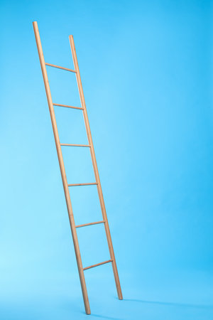 Modern wooden ladder on light blue backgroundの写真素材