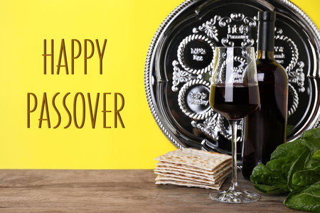 Symbolic Pesach (Passover Seder) items on wooden table against yellow background