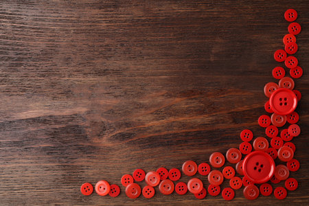 Many red sewing buttons on wooden background, flat lay. Space for textの写真素材