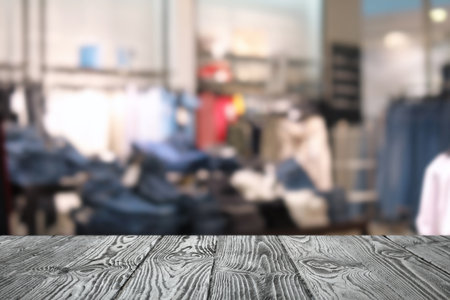 Empty wooden table and blurred view of store with modern clothesの写真素材