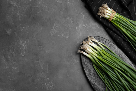 Fresh green spring onions on gray table, flat lay. Space for textの写真素材