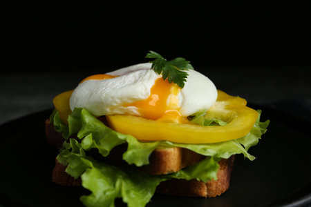 Delicious poached egg sandwich served on black plate, closeupの写真素材