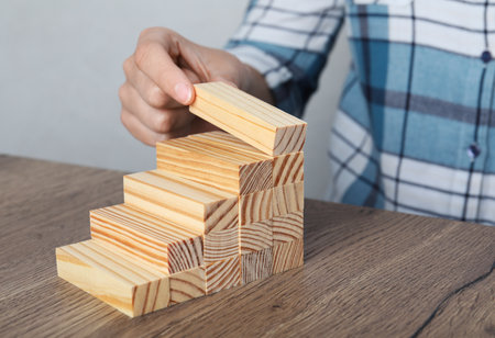 Woman building steps with wooden blocks at table, closeup. Career ladderの写真素材