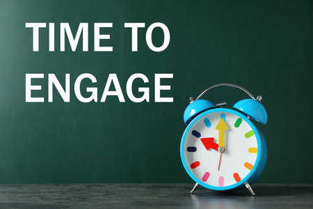 Text Time to engage on green chalkboard near alarm clockの写真素材