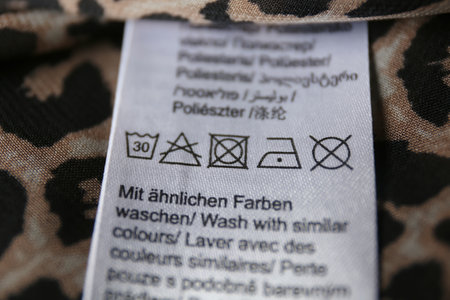Clothing label with care symbols on shirt, closeup view