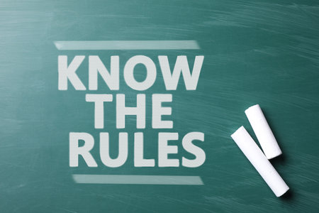 Phrase Know the rules and pieces of chalk on greenboard, top view