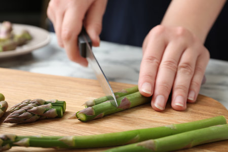 Woman cutting asparagus on wooden board, closeupの写真素材
