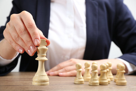 Woman with chess piece at wooden table, closeup. career promotion conceptの写真素材