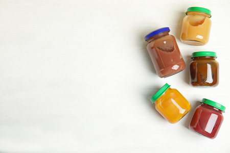 Jars with baby food on white wooden table, flat lay. Space for textの写真素材