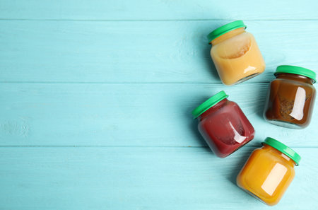 Jars with baby food on light blue wooden table, flat lay. Space for textの写真素材