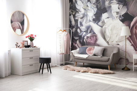 Stylish room interior with dressing table, mirror, sofa and floral wallpaperの写真素材