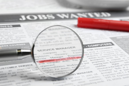 Looking through magnifying glass at newspaper, closeup. job search conceptの写真素材
