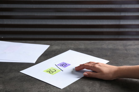Woman taking paper sheet with 80/20 rule representation at gray table, closeup. Pareto principle conceptの写真素材