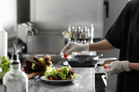 Female chef cooking tasty food in restaurant kitchen, closeupの写真素材