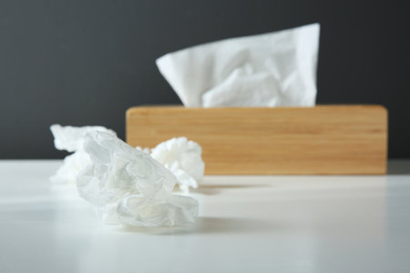 Used paper tissue and wooden holder on white table