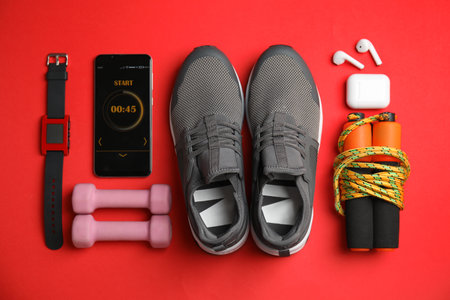 Smartphone with timer and fitness accessories on red background, flat layの写真素材
