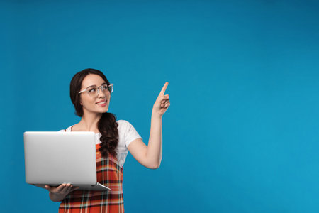 Young woman with laptop on blue background. Space for textの写真素材