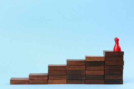 Red piece on wooden stairs against light blue background. career promotion concept