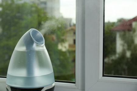 Modern air humidifier near window indoors, closeup. Space for text