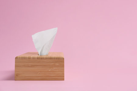 Wooden holder with paper tissue on pink background. Space for textの写真素材