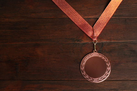 Bronze medal on wooden background, top view. space for designの写真素材