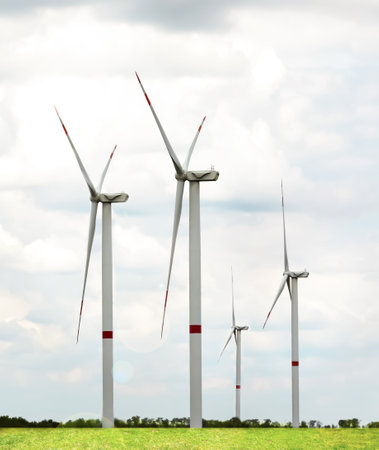 alternative energy sources. Wind turbines in field under cloudy sky