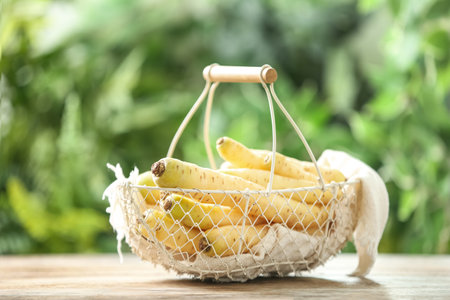 Raw white carrots in basket on wooden table against blurred backgroundの写真素材