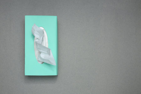 Box of paper tissue on gray background, top view. Space for text