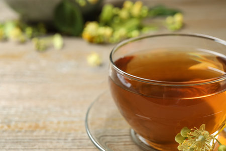 Cup of tea and linden blossom on wooden table, closeup. Space for textの写真素材