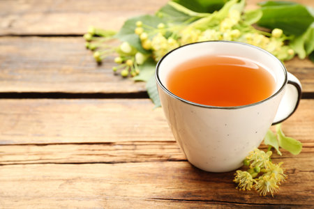 Cup of tea and linden blossom on wooden table. Space for textの写真素材