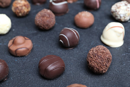 Different tasty chocolate candies on black table