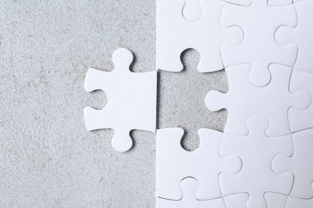 Blank white puzzle with separated piece on light gray stone background, flat layの写真素材