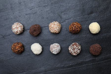 Different delicious chocolate candies on black table, flat layの写真素材