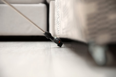 Spraying pesticide under furniture indoors, closeup. Pest control serviceの写真素材