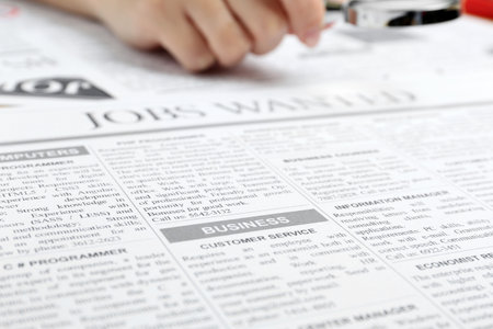Woman looking through magnifying glass at newspaper, closeup. job search concept