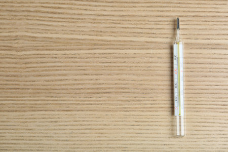 Mercury thermometer on wooden table, top view. Space for text