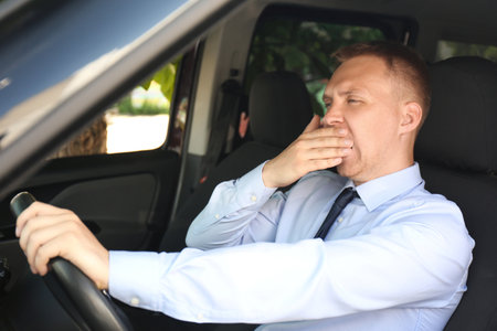 Tired young man yawning in his carの写真素材