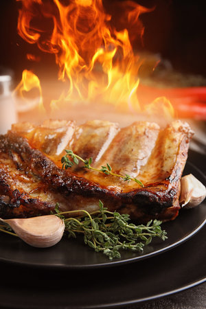 Tasty grilled ribs and flame on plate, closeupの写真素材