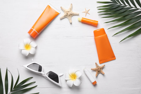 Frame of sun protection products and sunglasses on white wooden background, flat lay. Space for text