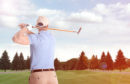 Young man playing golf on course with green grass, back view. space for designの写真素材