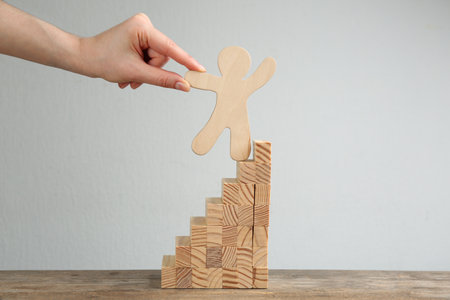 Closeup view of woman holding human figure on stairs at table. career promotion concept